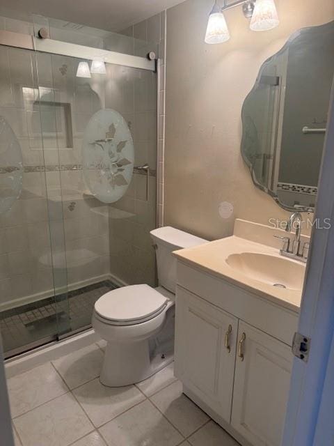 bathroom featuring vanity, toilet, tile patterned floors, and a shower with shower door