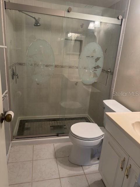 bathroom featuring vanity, toilet, walk in shower, and tile patterned flooring