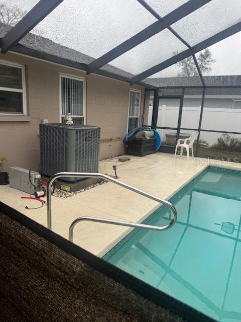 view of swimming pool with a patio area, a lanai, and central AC unit