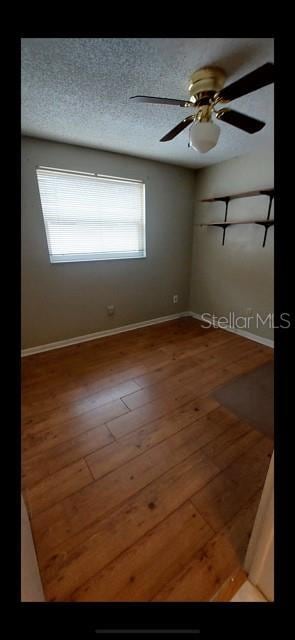 empty room with ceiling fan, a wealth of natural light, and hardwood / wood-style floors