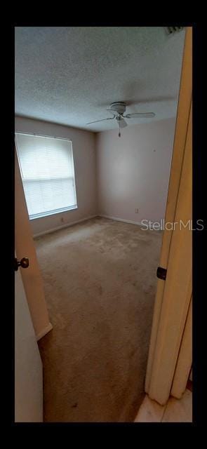 unfurnished room with light carpet, ceiling fan, and a textured ceiling