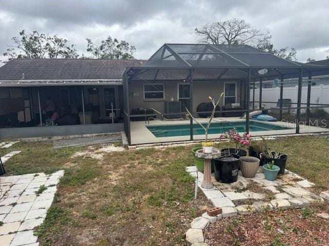 view of swimming pool with glass enclosure, a patio area, and a lawn