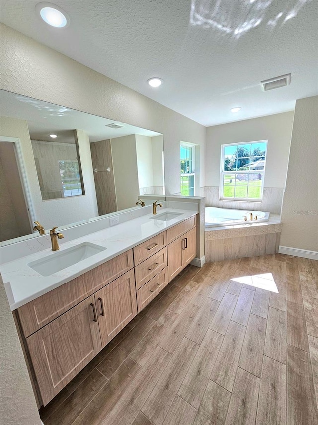 bathroom featuring a textured ceiling, vanity, and separate shower and tub