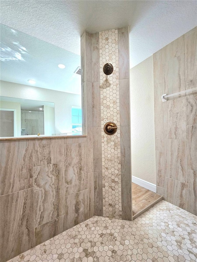 bathroom with a tile shower and a textured ceiling