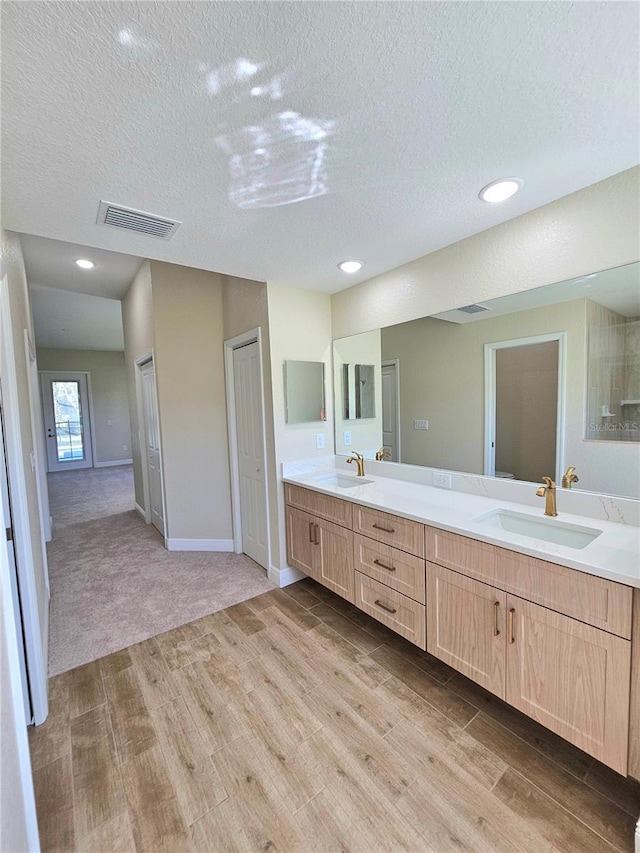 bathroom with a textured ceiling, vanity, and hardwood / wood-style flooring