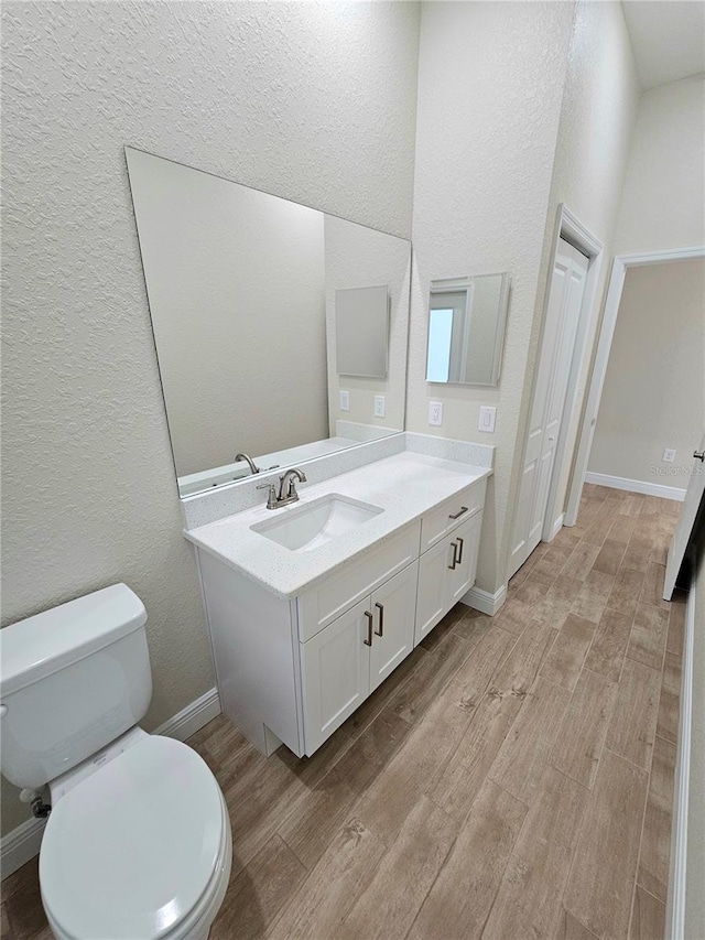 bathroom with hardwood / wood-style flooring, vanity, and toilet