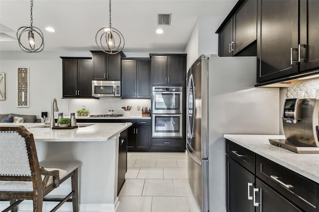 kitchen with a kitchen breakfast bar, light stone countertops, pendant lighting, and appliances with stainless steel finishes