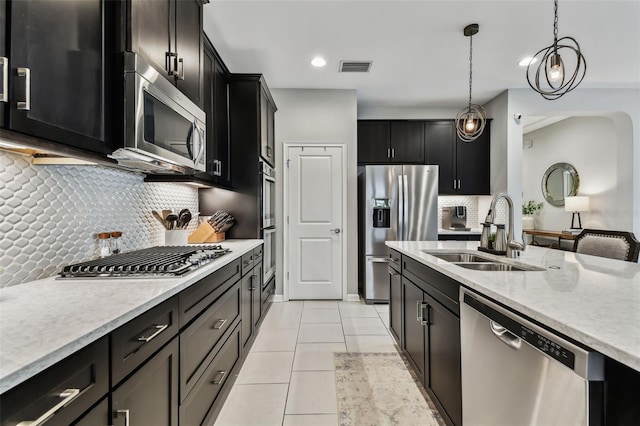 kitchen with decorative light fixtures, stainless steel appliances, tasteful backsplash, and sink