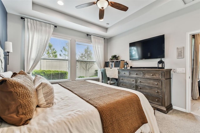 bedroom with ceiling fan, a tray ceiling, and multiple windows