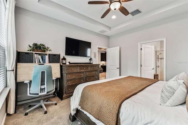 carpeted bedroom featuring a raised ceiling, connected bathroom, and ceiling fan