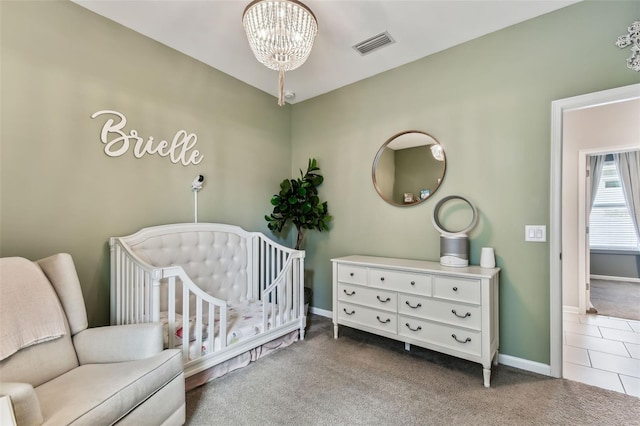 carpeted bedroom with a crib and a chandelier