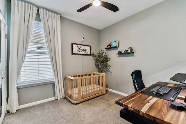 carpeted bedroom featuring multiple windows, a nursery area, and ceiling fan