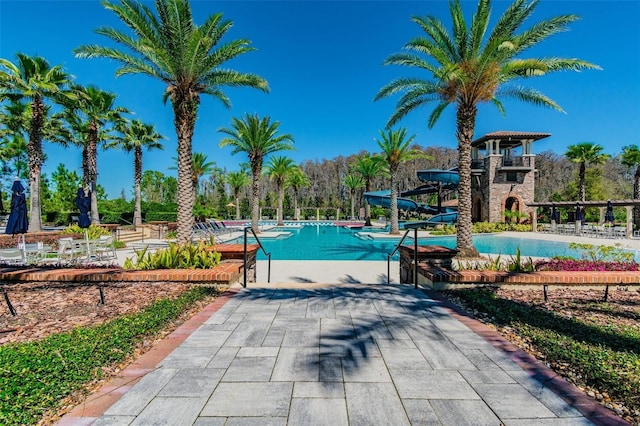 view of pool with a water slide and a patio