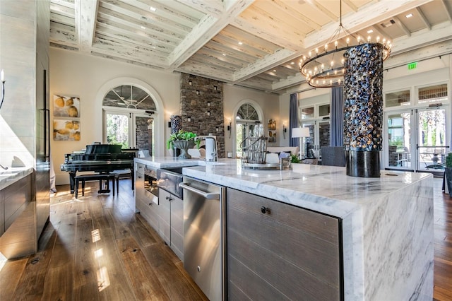 kitchen with dark wood-type flooring, french doors, beamed ceiling, a large island, and light stone counters