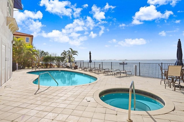 view of pool with a water view, a patio, and a hot tub