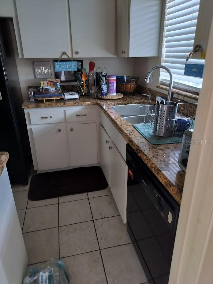 kitchen featuring white cabinetry, dishwasher, light tile patterned flooring, and sink