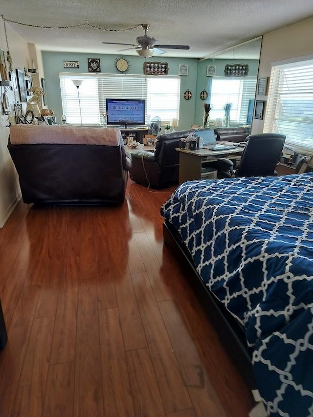 bedroom featuring dark hardwood / wood-style flooring, a textured ceiling, and ceiling fan