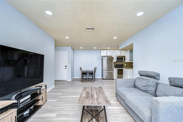 living room featuring light hardwood / wood-style floors and a textured ceiling