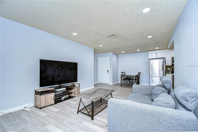 living room with a textured ceiling and light hardwood / wood-style floors