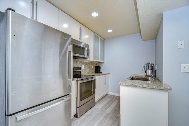 kitchen featuring appliances with stainless steel finishes, backsplash, white cabinetry, and sink