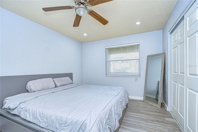 bedroom featuring ceiling fan, light hardwood / wood-style flooring, and a closet