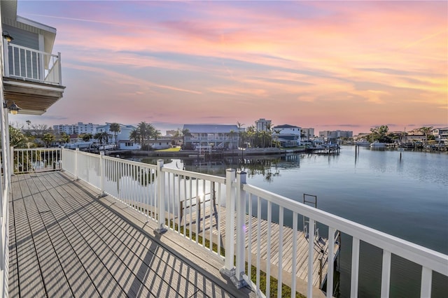 deck at dusk featuring a water view