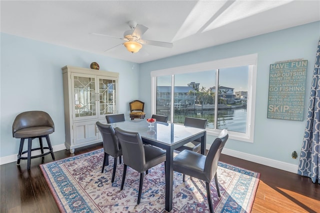 dining room featuring ceiling fan, dark hardwood / wood-style flooring, and a water view