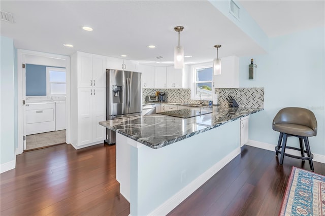 kitchen featuring kitchen peninsula, appliances with stainless steel finishes, tasteful backsplash, pendant lighting, and white cabinetry