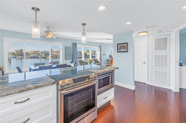 kitchen with a water view, white cabinets, stainless steel appliances, and decorative light fixtures