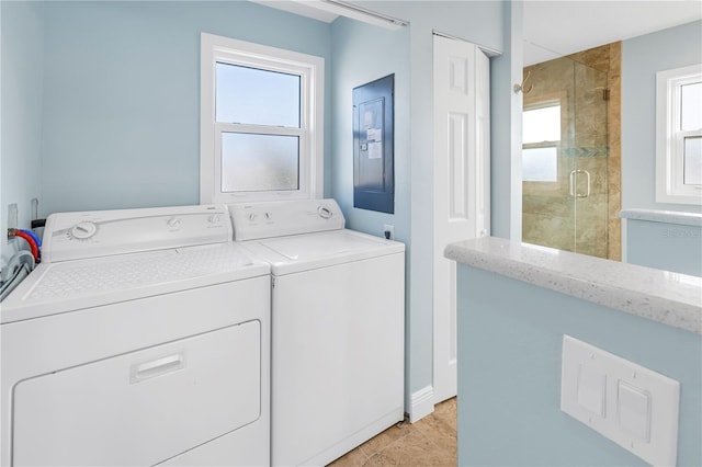 washroom featuring separate washer and dryer, electric panel, light tile patterned floors, and a healthy amount of sunlight