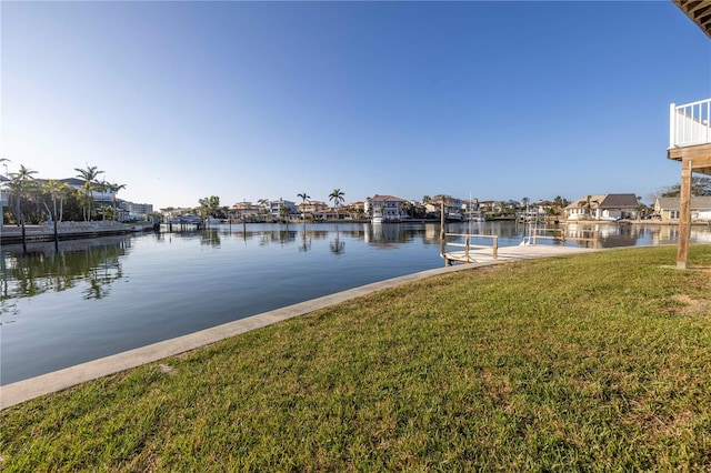 view of dock with a lawn and a water view