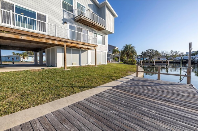 view of dock with a water view and a lawn