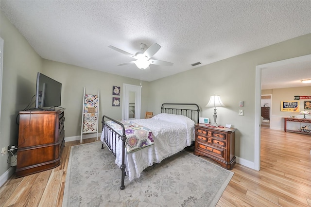 bedroom with ceiling fan, a textured ceiling, and light wood-type flooring