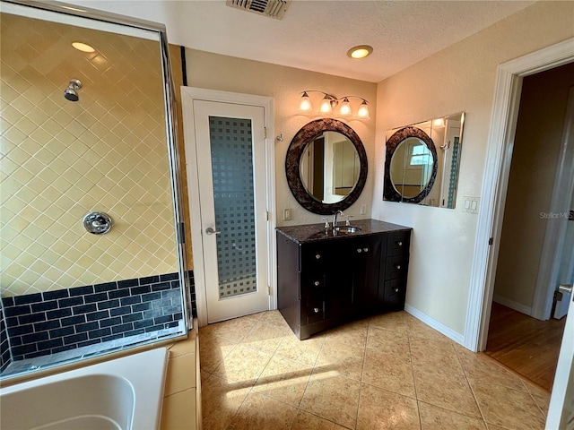 bathroom featuring tile patterned floors, a tub, vanity, and a textured ceiling