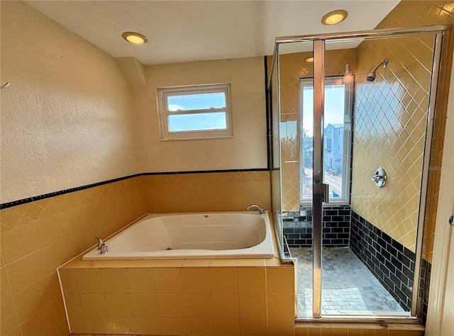 bathroom featuring tile walls and independent shower and bath