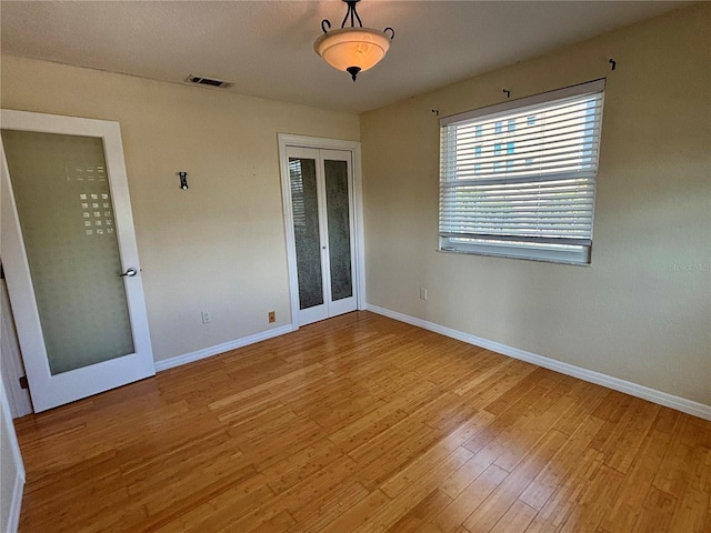 empty room with french doors and light hardwood / wood-style floors