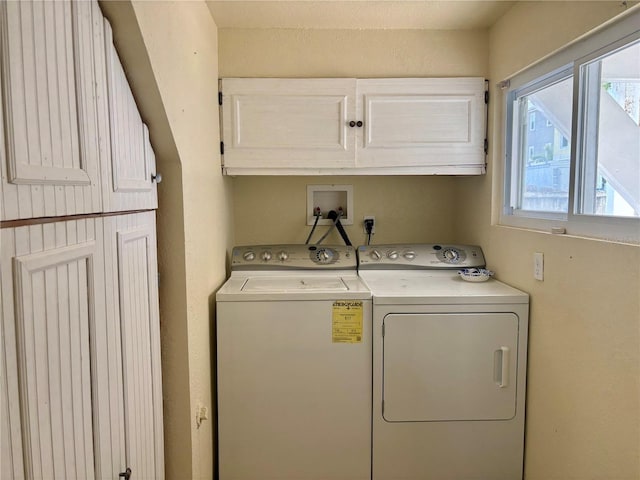 laundry room featuring washing machine and clothes dryer and cabinets