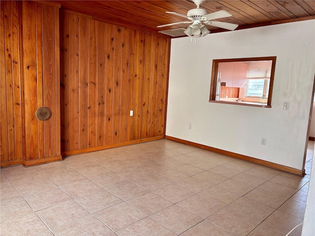 tiled spare room with ceiling fan, wood ceiling, ornamental molding, and wooden walls