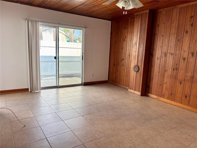 tiled spare room featuring wood walls, ceiling fan, and wooden ceiling