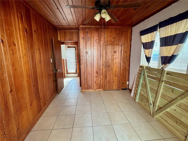 hallway with light tile patterned flooring, wooden walls, and wood ceiling