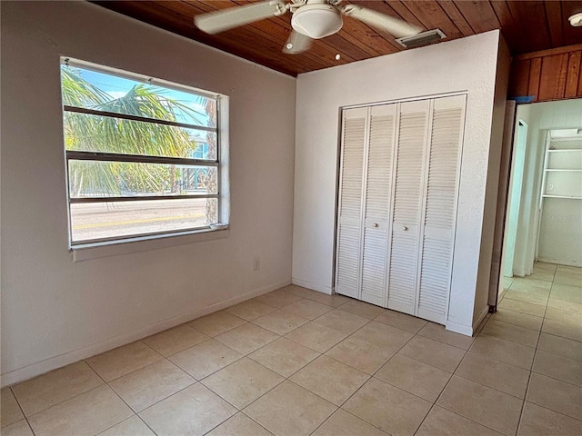 unfurnished bedroom with light tile patterned floors, a closet, ceiling fan, and wood ceiling