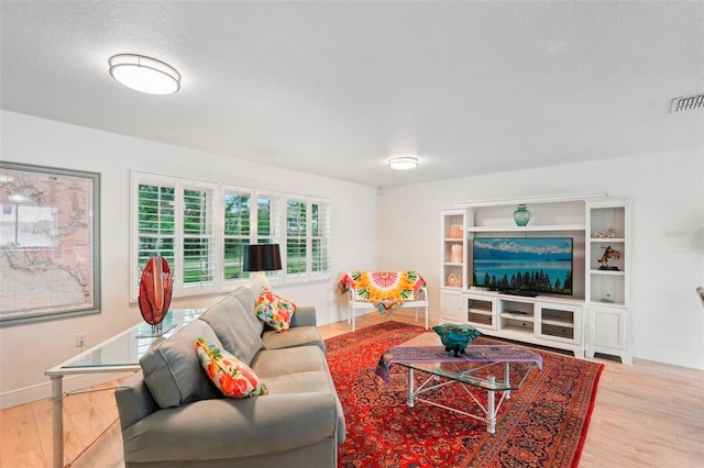 living room featuring light wood-type flooring and a textured ceiling