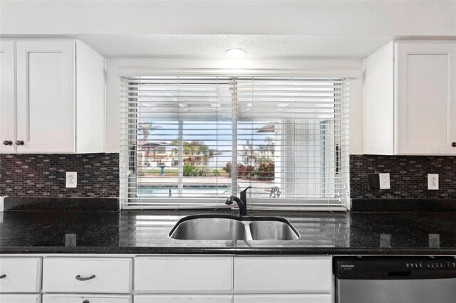 kitchen featuring stainless steel dishwasher, backsplash, white cabinetry, and sink