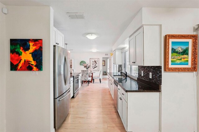 kitchen with decorative backsplash, white cabinetry, sink, and appliances with stainless steel finishes