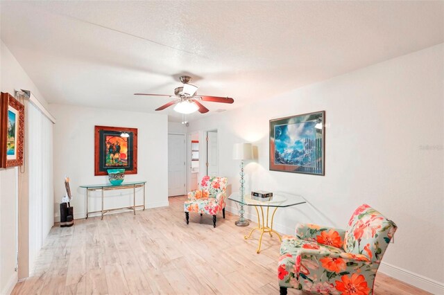 living area featuring a textured ceiling, light hardwood / wood-style floors, and ceiling fan