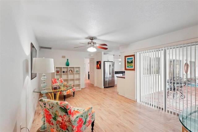 kitchen with light hardwood / wood-style floors, ceiling fan, stainless steel fridge, and white cabinetry