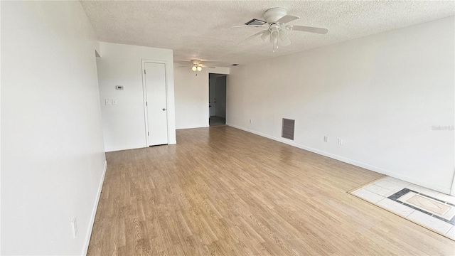 empty room featuring ceiling fan, light hardwood / wood-style flooring, and a textured ceiling