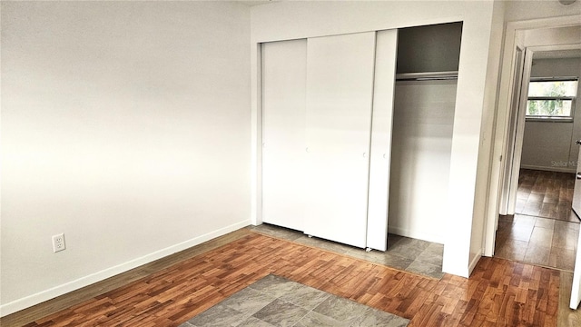 unfurnished bedroom featuring dark hardwood / wood-style flooring and a closet