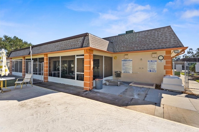 rear view of house featuring a sunroom and a patio