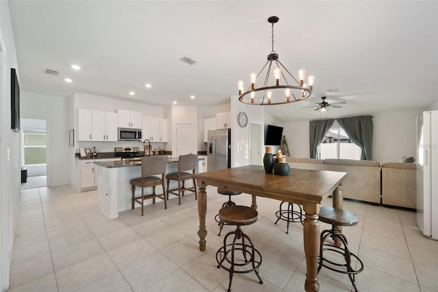 tiled dining space featuring ceiling fan with notable chandelier and sink